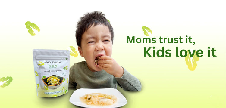 Young child happily eating Baek Kimchi with the slogan ‘Moms trust it, Kids love it’ on a green background, product packaging displayed.